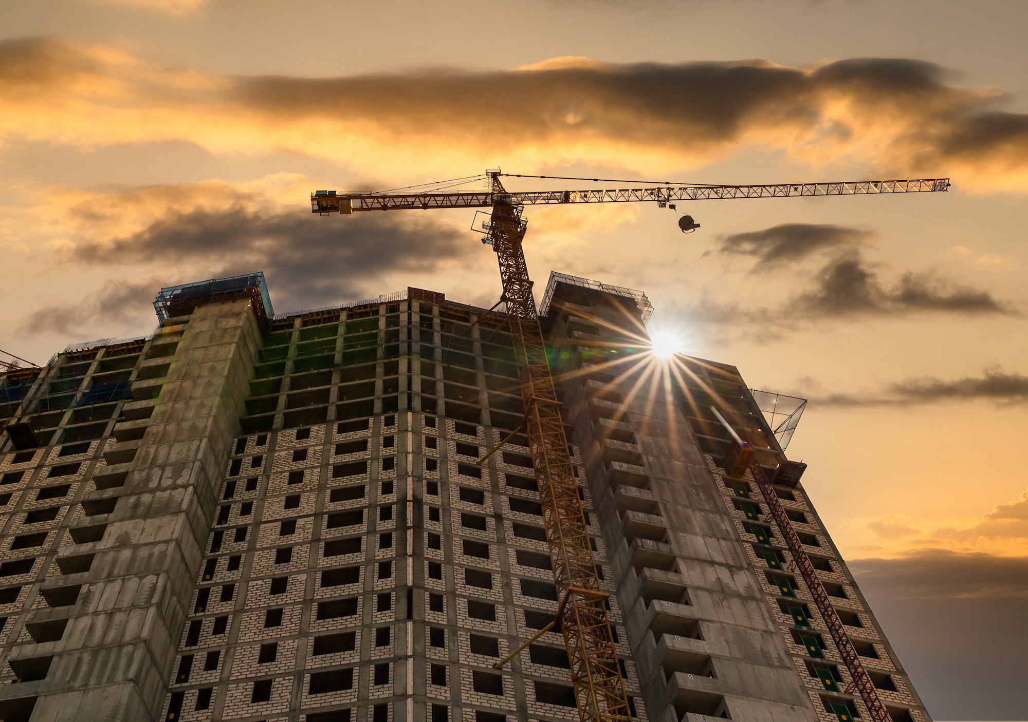 Construction crane and the building against the sunset sky Construction crane and the building against the sunset sky