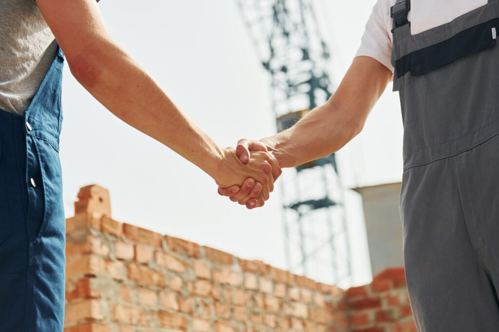 Doing handshake. Two construction workers is together at the building