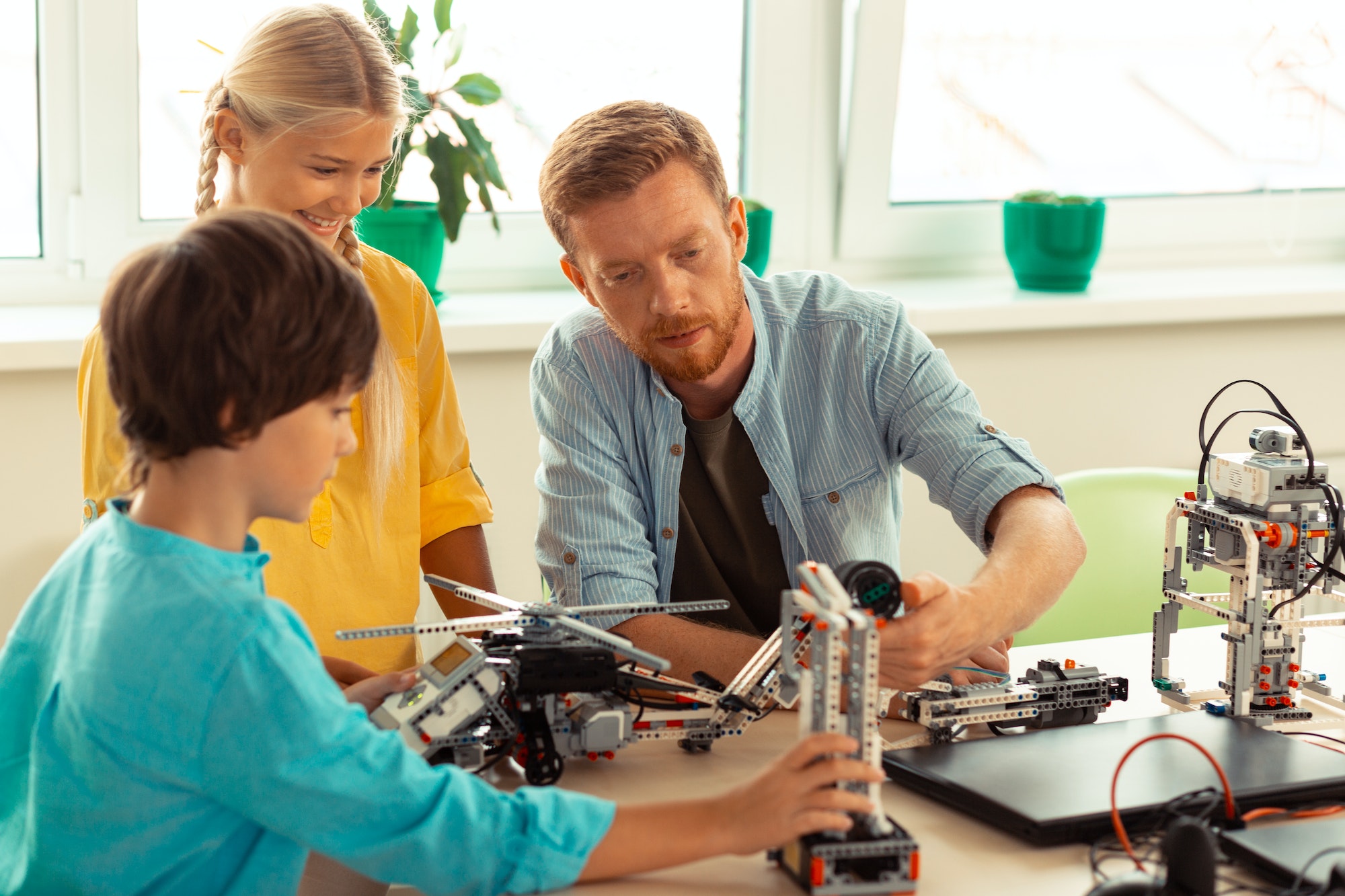 Teacher helping pupils building with construction set Teacher helping pupils building with construction set